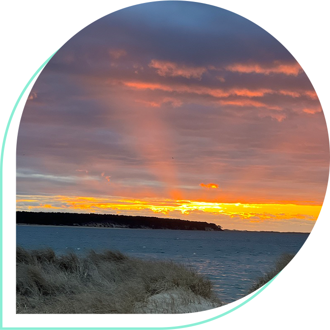 A sunset over the ocean with a rainbow in the sky.